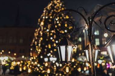 Açık hava tatil pazarında klasik dekoratif lanterler, arka planda büyük bir noel ağacı 