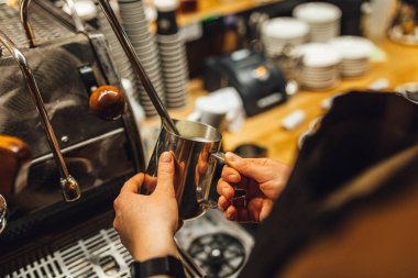 Metal sürahide süt buharı tüten Barista 'yı kapat. Barista kahve yapıyor..