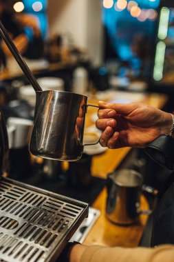 Metal sürahide süt buharı tüten Barista 'yı kapat. Barista kahve yapıyor..
