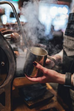 Kahve dükkanında kahve için süt buharı yapan barista. Kahve makinesi.