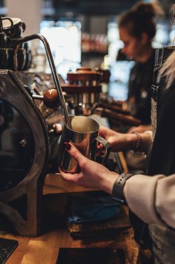 Kahve dükkanında kahve için süt buharı yapan barista. Kahve makinesi.