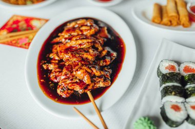 Beyaz tabakta Asya yemekleri, parlak arka plan tatlı tavuk, suşi, börek..