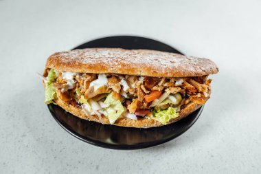 Koyu tabağa yerleştirilmiş kebaplı sandviçin görüntüsünü kapat, parlak arkaplan