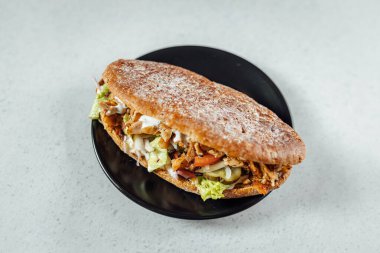 Koyu tabağa yerleştirilmiş kebaplı sandviçin görüntüsünü kapat, parlak arkaplan