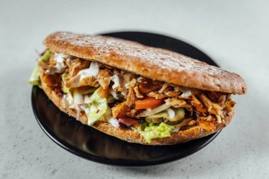 Koyu tabağa yerleştirilmiş kebaplı sandviçin görüntüsünü kapat, parlak arkaplan