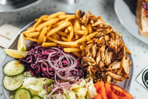 Doner Kebab on plate with vegetables fries and souce, grilled meat on plate