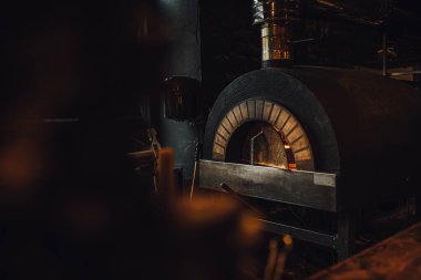 Lokantada ateş olan koyu tuğlalı pizza fırını. 