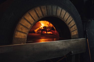 Lokantada ateş olan koyu tuğlalı pizza fırını. 