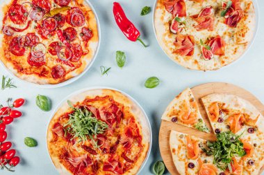 Parlak masada servis edilen leziz İtalyan pizzaları, yukarıdan çekilen malzemelerle, pizzacıda.