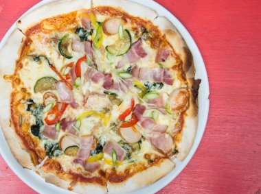 Kırmızı ahşap masa üzerinde peynir erime ile sıcak pizza dilimi. 