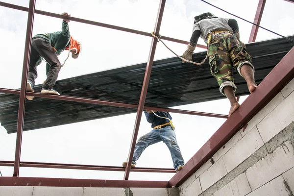 Pracowników budowlanych pokryć dachowych zainstalować blachy na dachu. — Zdjęcie stockowe