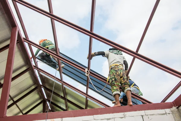 Roofing construction workers  install metal sheet on the roof.