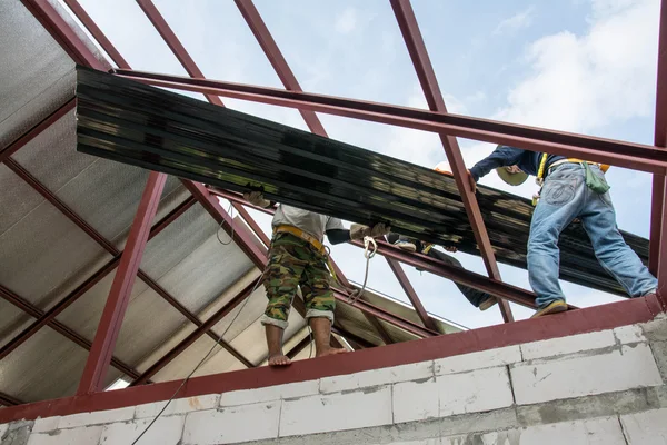 Takläggning byggnadsarbetare installerar plåt på taket. — Stockfoto