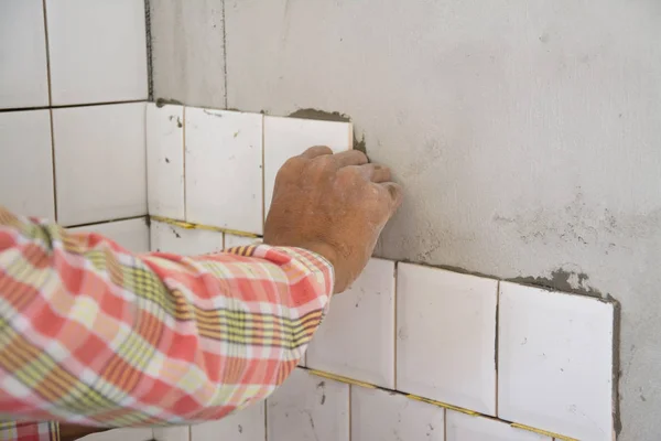 laying ceramic tiles on wall, installing tiles  in construction site.