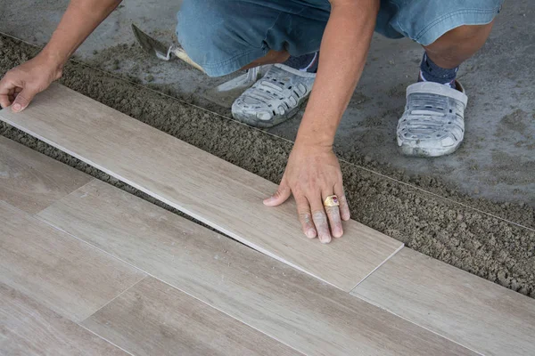 Laying ceramic wood tiles on wall, installing tiles  in construction site. — Stock Photo, Image