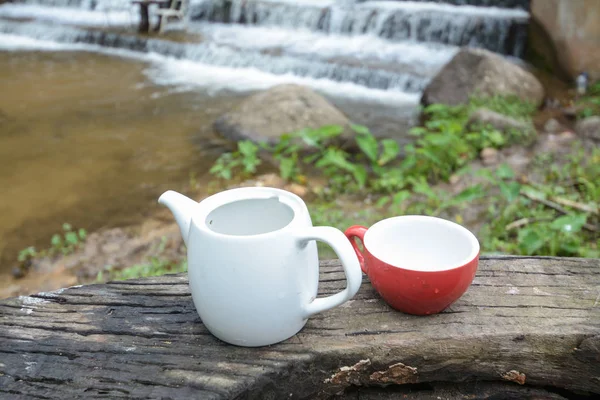 Tasse Tee auf Holzdecktisch mit Wasserfall — Stockfoto