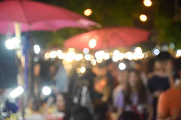 Unscharfes Bild von Menschen, die nachts auf dem Markt spazieren — Stockfoto