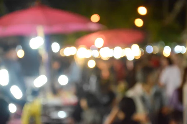 Blurred image of people walking in market at night — Stock Photo, Image
