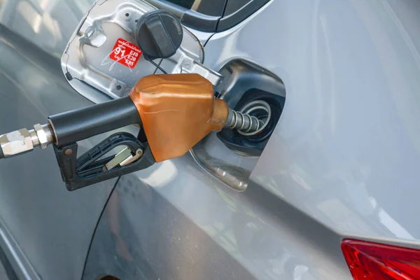 Sosteniendo la boquilla de combustible y el coche de repostaje en la gasolinera —  Fotos de Stock