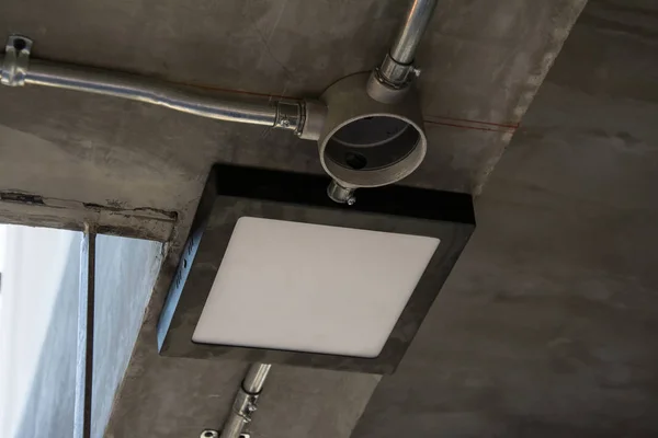 Lampe moderne avec tuyau métallique sous le plafond en béton — Photo