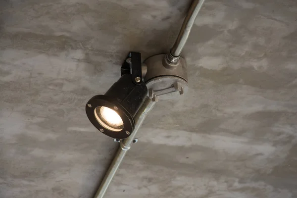 Современная лампа с металлической трубой под бетонным потолком — стоковое фото
