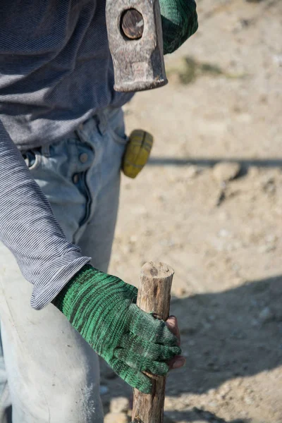 Работник использует молоток для стука деревянный столб — стоковое фото