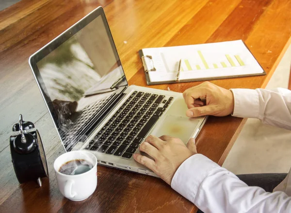 Uomo d'affari che lavora con laptop, documenti e caffè su legno — Foto Stock
