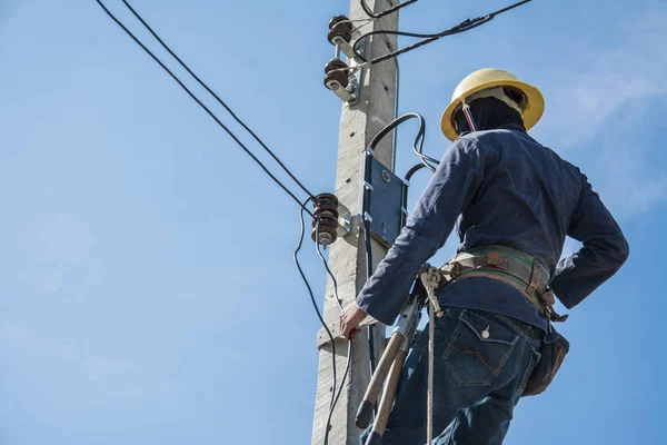 Eletricista trabalhando no pólo de energia elétrica com céu azul — Fotografia de Stock