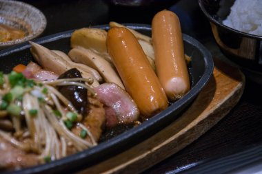 sosis sıcak tava üzerinde mantar ile ateş.