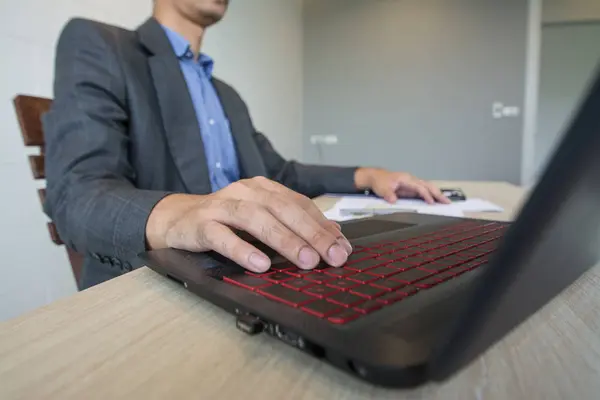 Uomo d'affari che lavora con laptop e documenti su tavolo in legno — Foto Stock