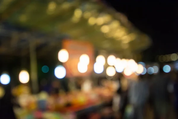 Blurred image of people walking in market at night — Stock Photo, Image