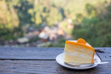 Doğa manzaralı ahşap masada turuncu pasta..