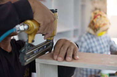 Marangoz yeni mobilya yapmak için havalı silah kullanır. 