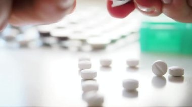 Kadın beyaz masadaki tabaktan beyaz haplar çıkarıyor. Makro, kapat.