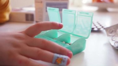 Çocuk ecza organizatörünü beyaz ve kahverengi haplarla kapatıyor.
