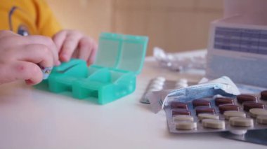 Çocuk ecza organizatörünü beyaz ve kahverengi haplarla kapatıyor.