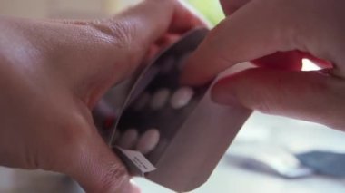 Kadın kutudan bir tabak beyaz hap alıyor ve bir tane alıyor. Makro