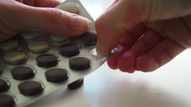 Wanita mengeluarkan pil putih dan coklat dari piring di atas meja putih Tutup — Stok Video