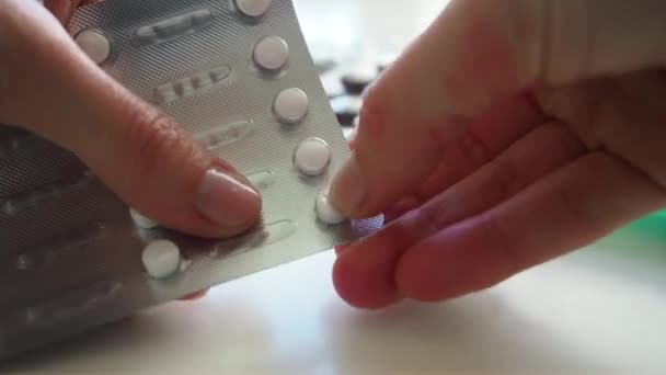 Woman pulls out white pills out of the plate on the white table. Close up — Stock Video