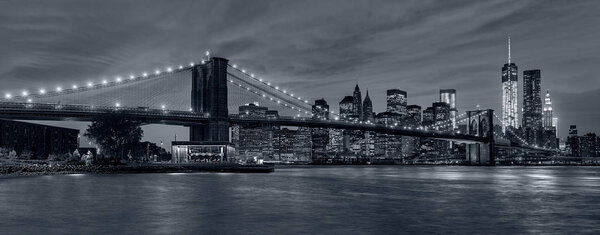 Panoramic view New York City downtown skyline at night and Manhattan Bridge in blue tonality