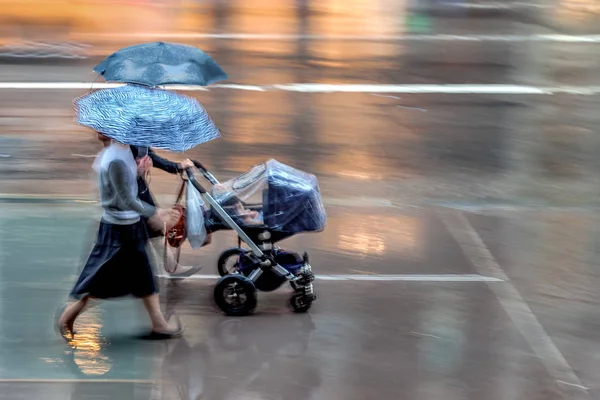 Madre con bambini in una strada di città sotto la pioggia — Foto Stock