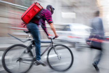 Maskeli iş adamları, yağmurlu bir günde şehir yolunda trafikte motosikletle teslimat yapıyor.