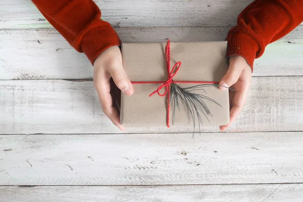 Bir Noel hediyesi tutan bir kırmızı kazaklı kadın — Stok fotoğraf