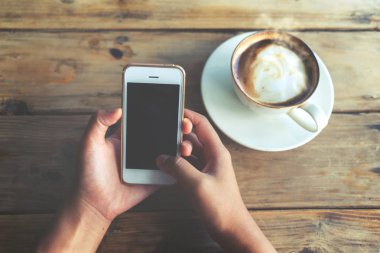 sıcak kahve fincanı ile mobil akıllı telefon kafe dükkanında holding kadının eller