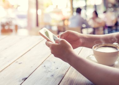  sıcak kahve fincanı ile mobil akıllı telefon kafe dükkanında holding kadının eller