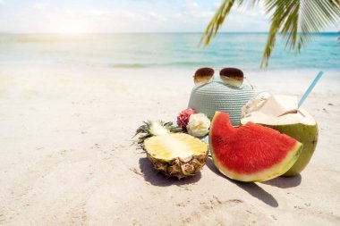  şapka, güneş gözlüğü ve kumlu plaj tropikal meyve