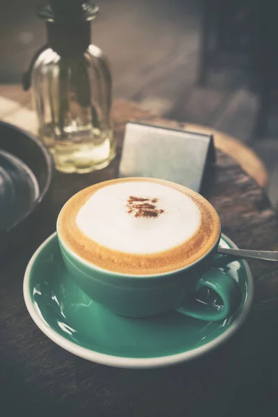 Cappuccino quente em xícara de café verde na mesa de madeira no café — Fotografia de Stock