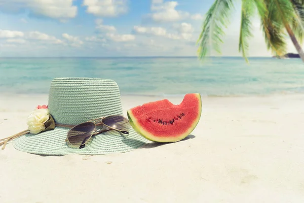 sunglasses and melon fruit on sandy tropical beach