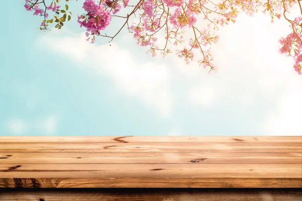 wood table with pink cherry blossom flower on sky background
