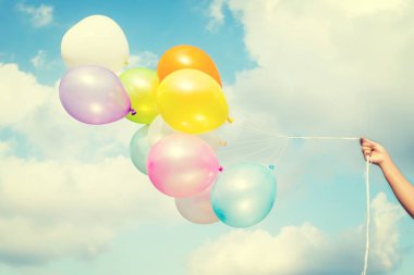 Kadın el renkli balonlar mavi gökyüzü üzerinde tutarak 
